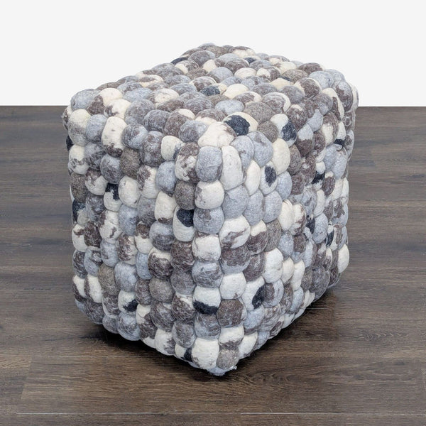 Shaggy checkerboard wool pouf in neutral tones, styled as a modern ottoman seat.  