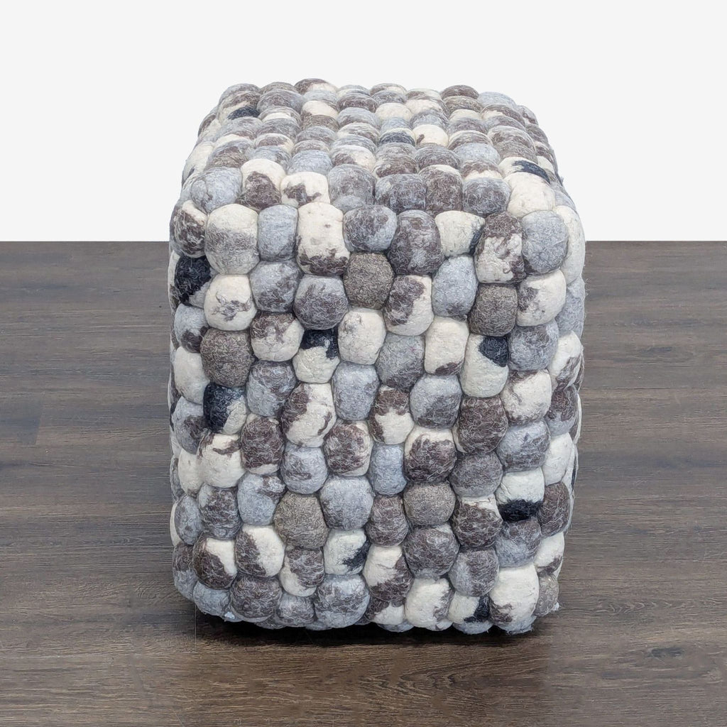 Textured wool pouf with a bold checkered pattern, suitable for use as a cozy stool.  