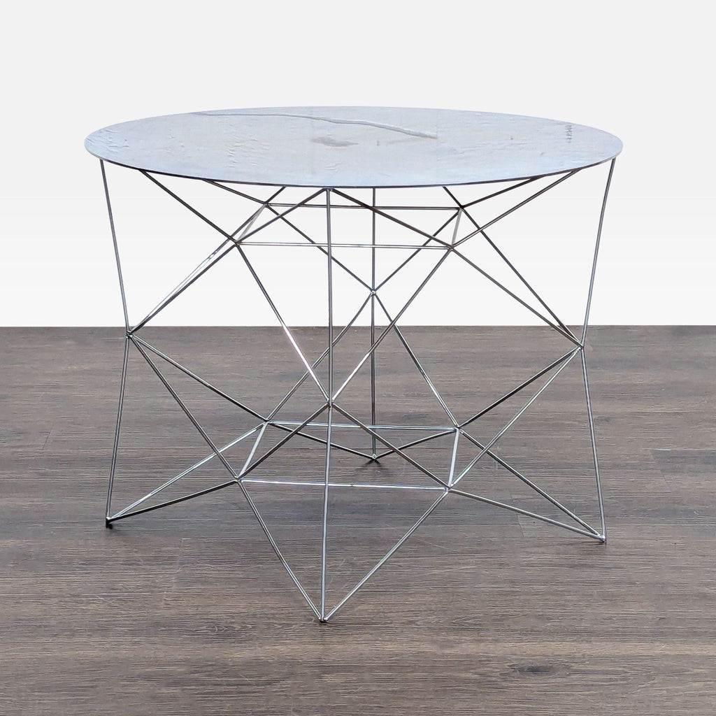 3. West Elm round side table with a thin marble top and angular crisscross metal frame, on dark wood.