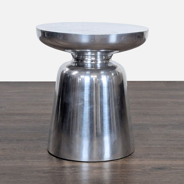 1. Modern metallic side table with a rounded top and flared base, displayed on a dark wood floor.
