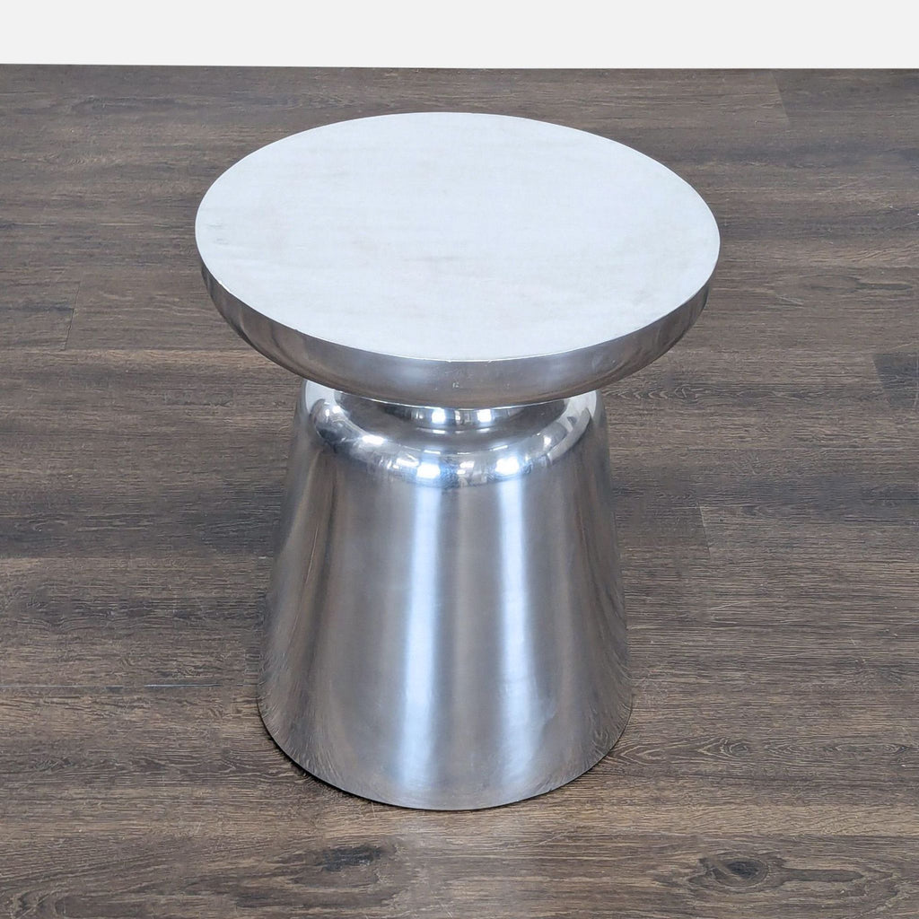 2. Top-down view of a round, silver side table with a reflective finish on a wooden surface.