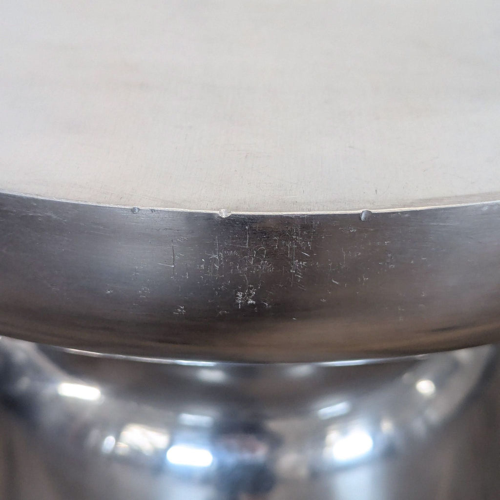 3. Close-up of a brushed metal table edge showing minor scratch marks and surface details.
