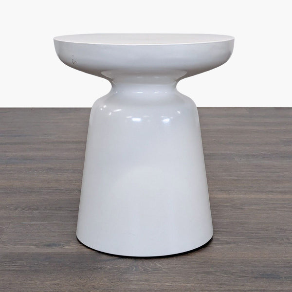1. Modern white West Elm side table with a glossy hourglass shape on a wood floor, front view.