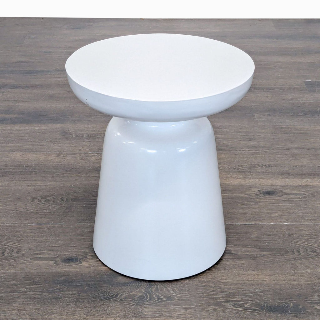 2. Round white West Elm side table with pedestal base, shown from an angled side perspective.