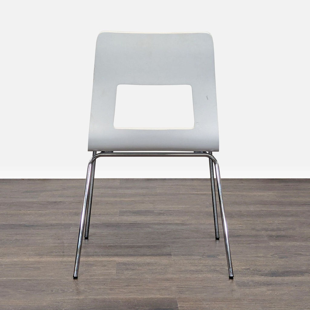 2. Front view of a minimalist dining chair featuring a white seat, cutout backrest, and metal frame.