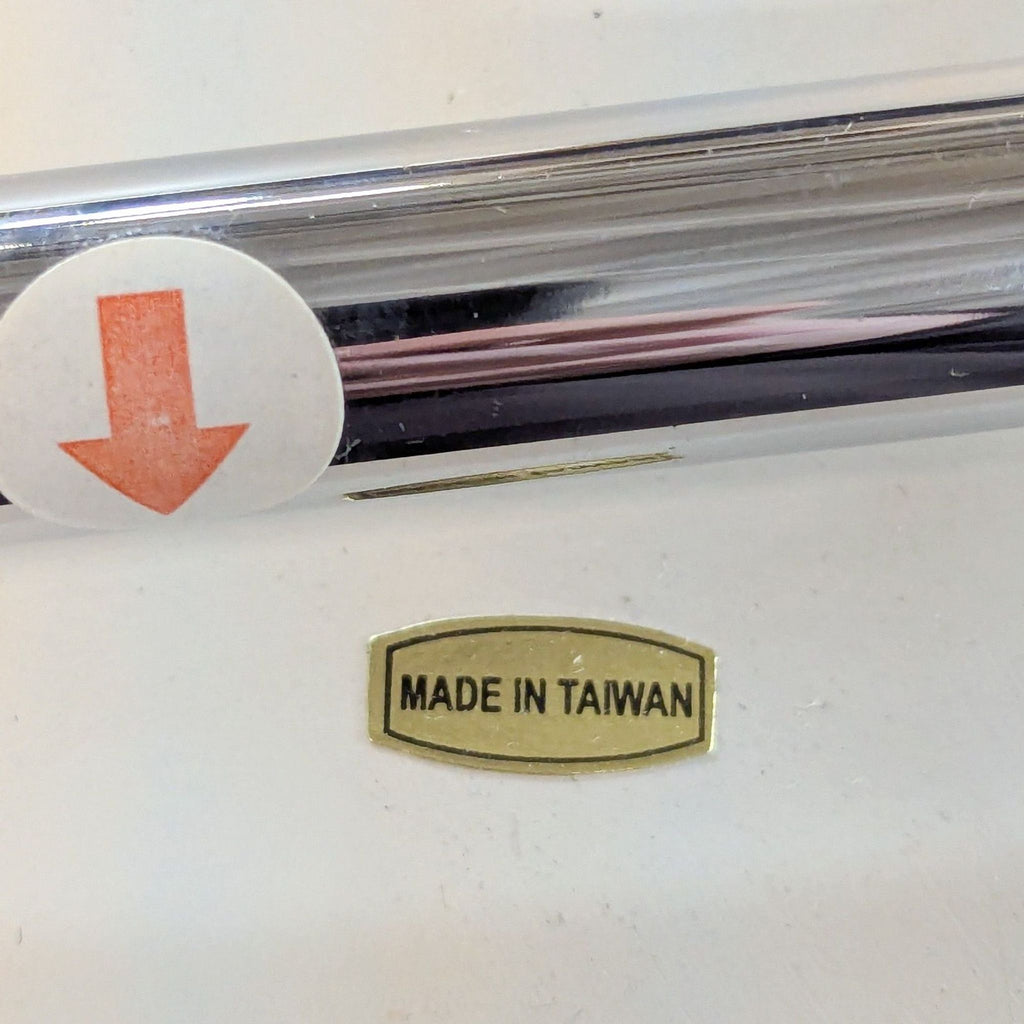 3. Close-up of chair's chrome leg with a "Made in Taiwan" label and red arrow sticker on white background.