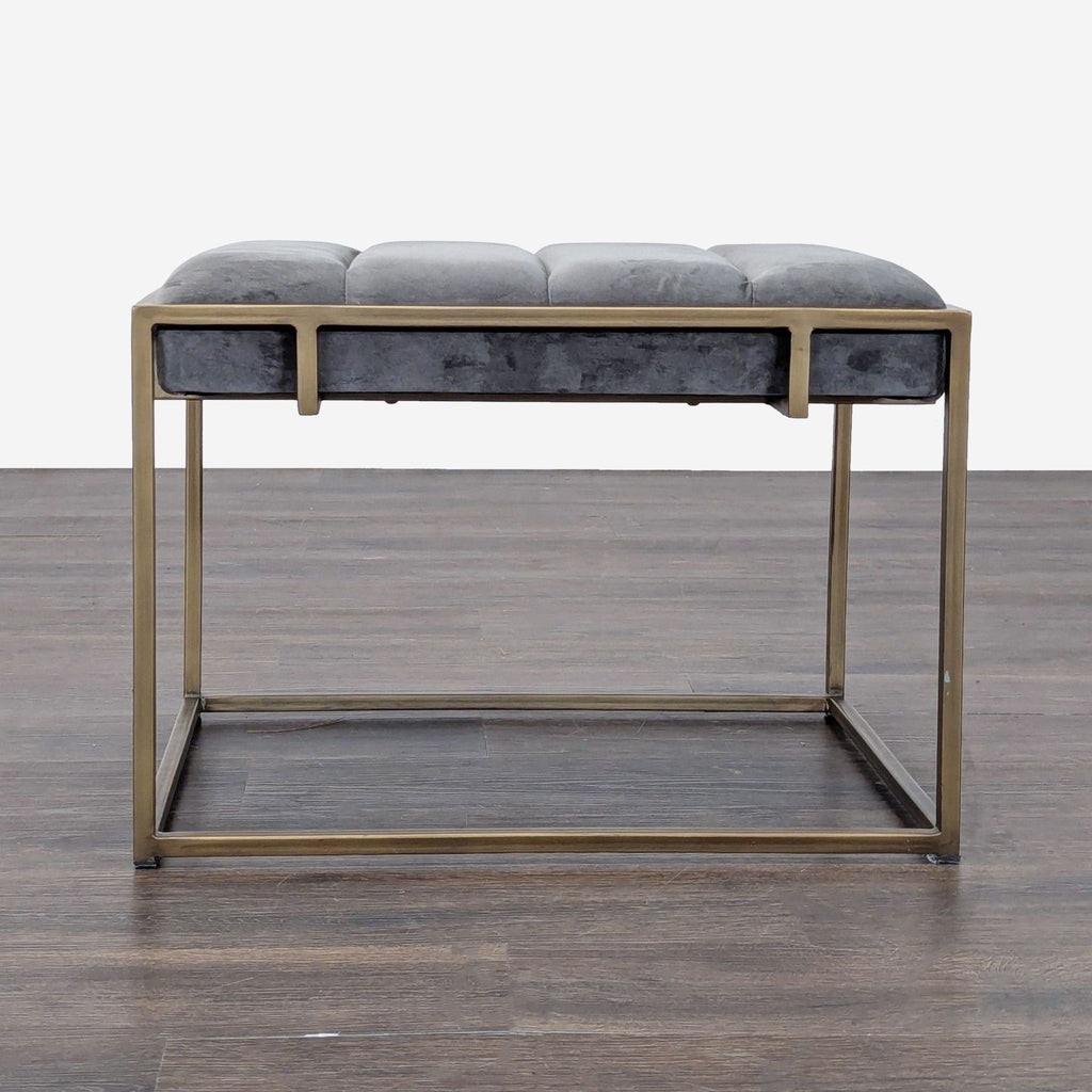 1. Modern bench with a gold metal frame and gray tufted cushion, shown on a wood floor, front view.