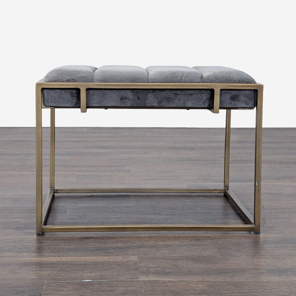 1. Modern bench with a gold metal frame and gray tufted cushion, shown on a wood floor, front view.