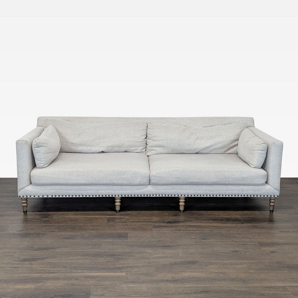 Pottery Barn 3-seat sofa with neutral fabric, wooden legs, and nailhead trim in a modern design.