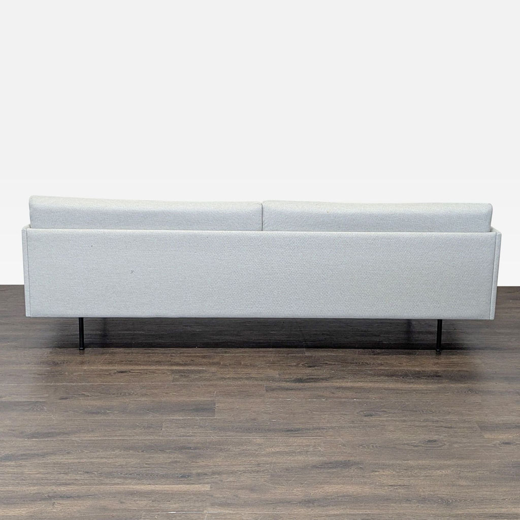 Three-seat sofa by Muuto: light-toned fabric, slim black legs, simple lines, and comfortable cushions.