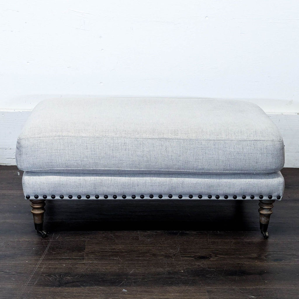 1. Upholstered ottoman with pillow top and elegant turned wooden feet, perfect for living spaces.