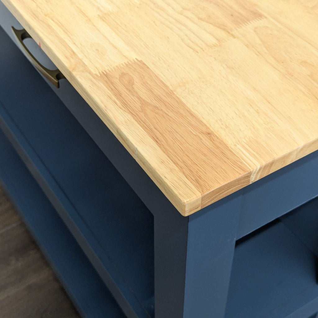 3. Close-up of the Twin Star Home kitchen island’s natural wood top and blue frame with gold handle.