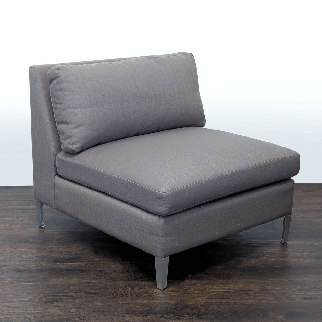 Modern gray lounge chair from CB2 with sturdy metal legs, ideal for relaxing in living rooms or lounges.
