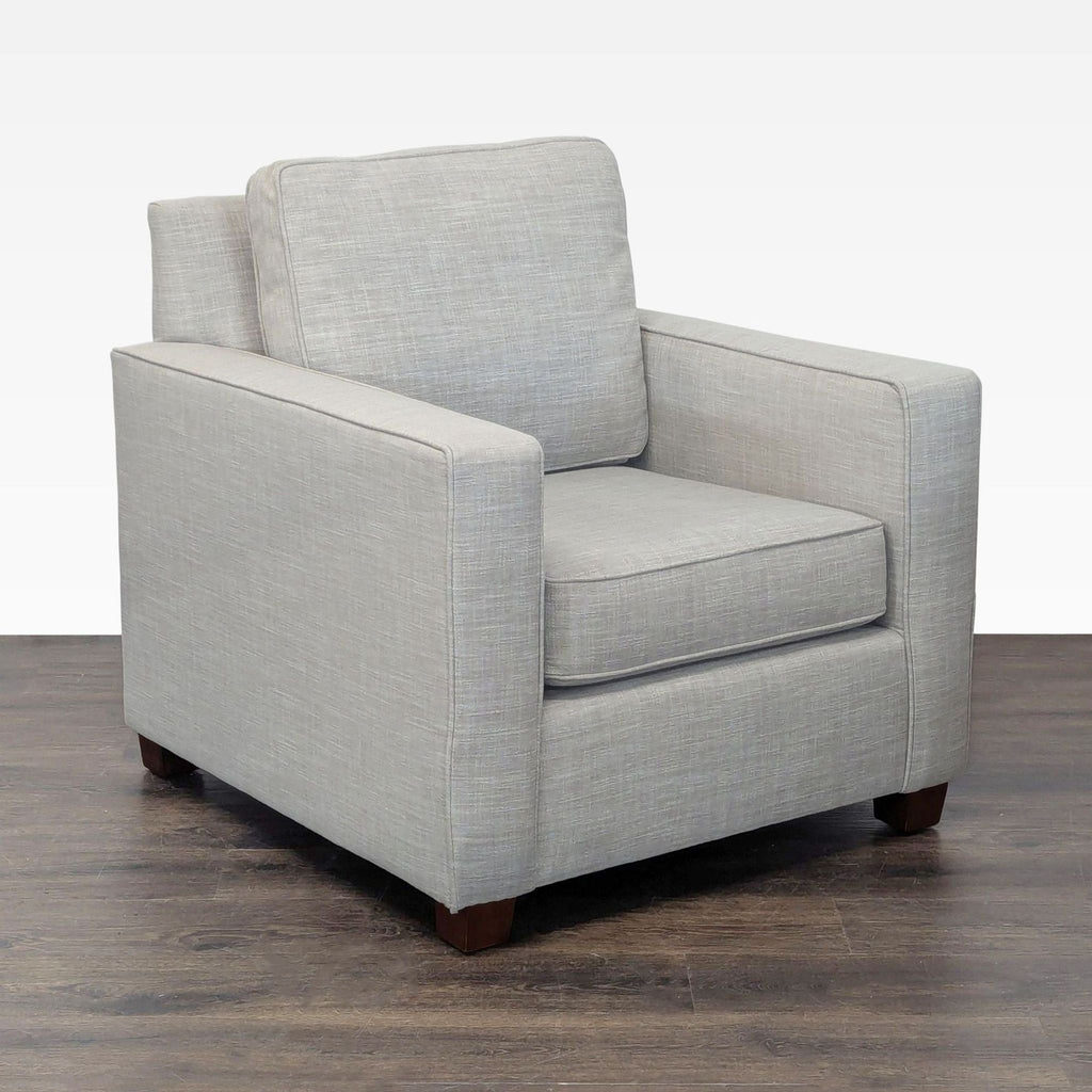 Modern West Elm armchair featuring clean lines, a supportive back, and durable wood legs in a lounge setting.  