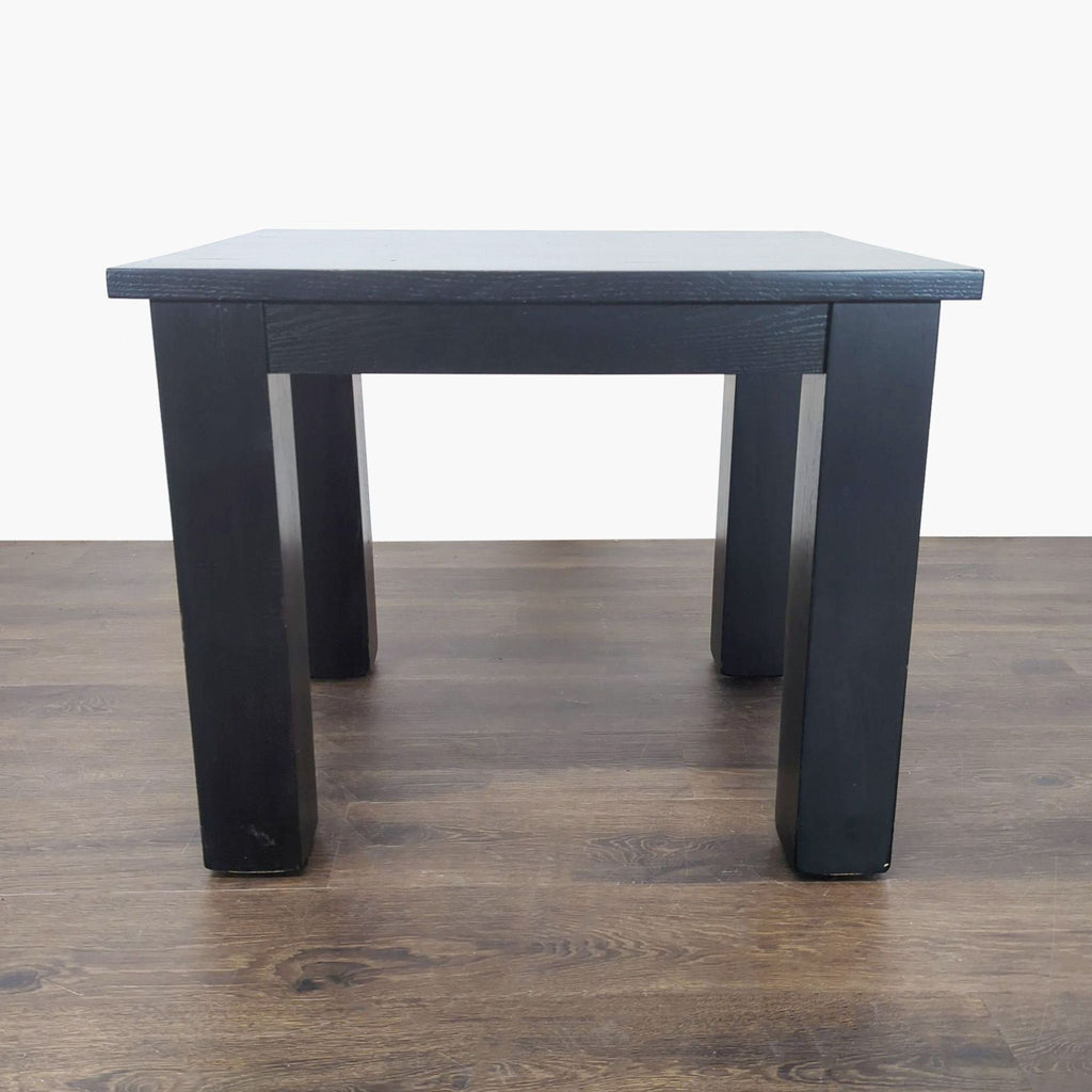 1. Black wooden end table with thick square legs, shown against a white background and wooden floor.