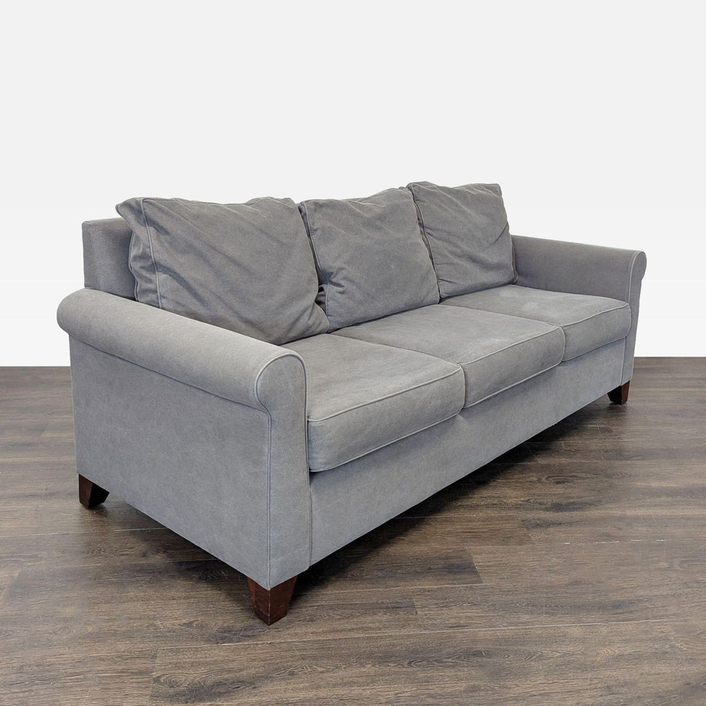 2. Angled side view of a gently used Pottery Barn gray 3-seat sofa with plush cushions and classic design.
