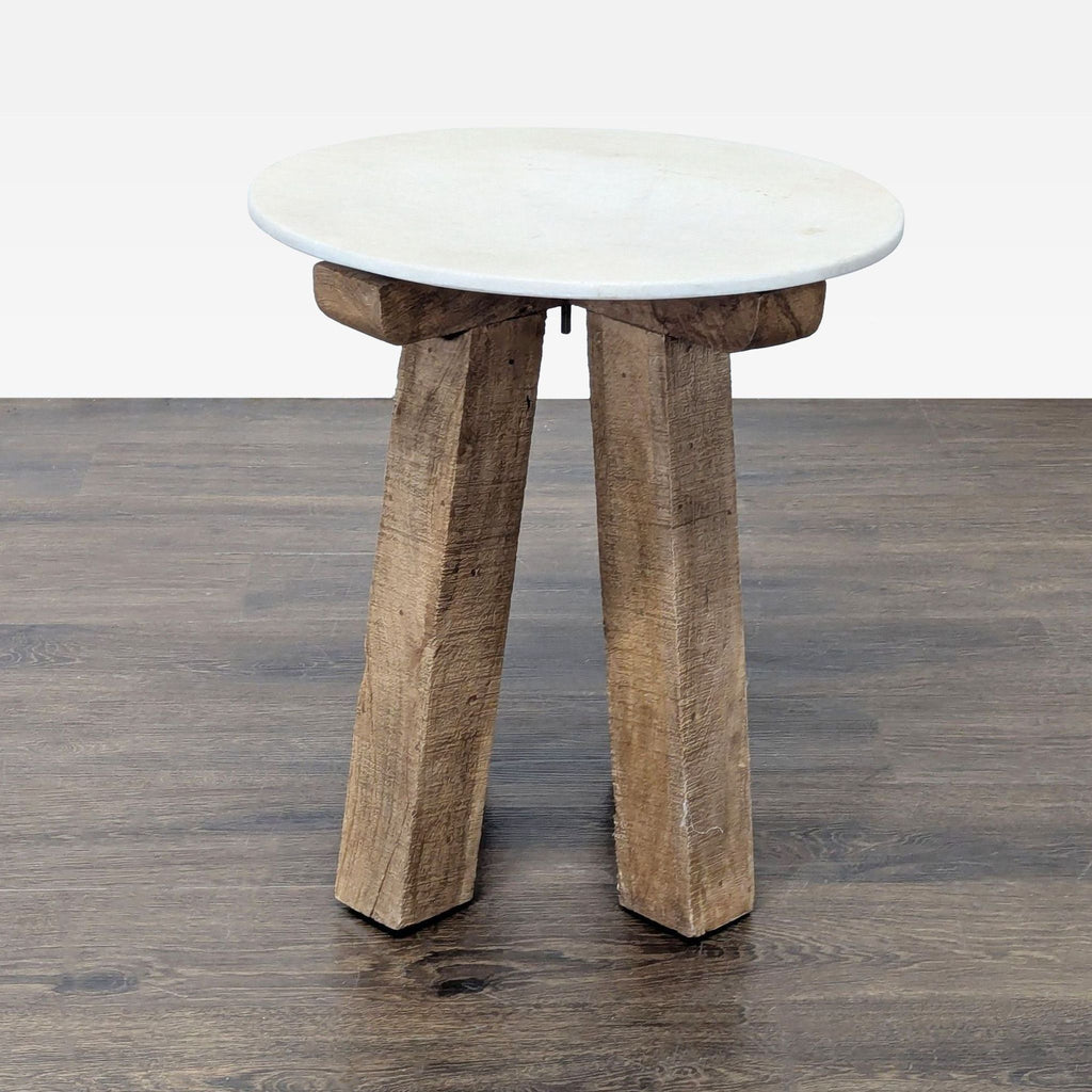 2. Modern Anthropologie console table featuring a circular white surface and three rustic wooden legs.