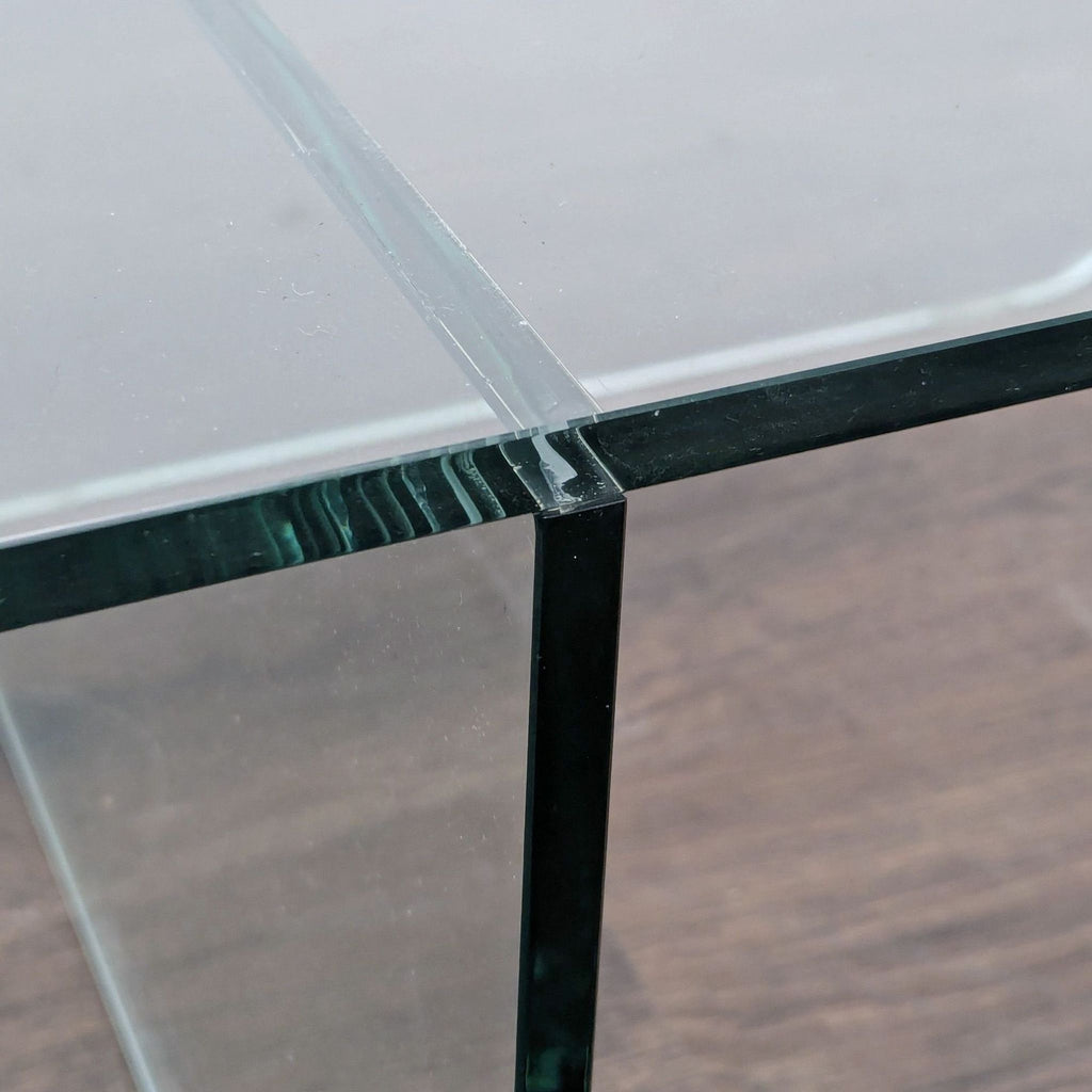 1. Close-up of EQ3 coffee table showing thick glass panels joined at a right angle, with visible polished edges.