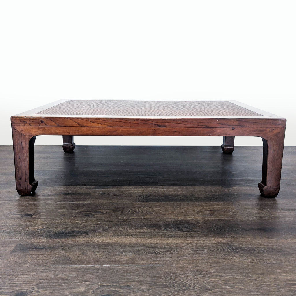 1. Rectangular wooden coffee table with wide legs and woven rattan top, viewed from the side on a dark floor.
