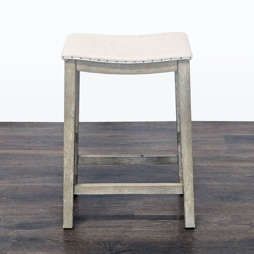 Upholstered stool with nailhead trim from Pottery Barn, ideal for modern seating or décor.  