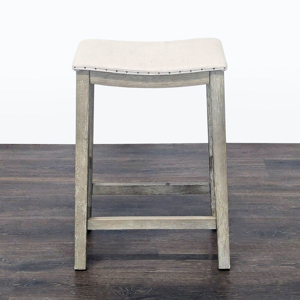 Upholstered stool with nailhead trim from Pottery Barn, ideal for modern seating or décor.  
