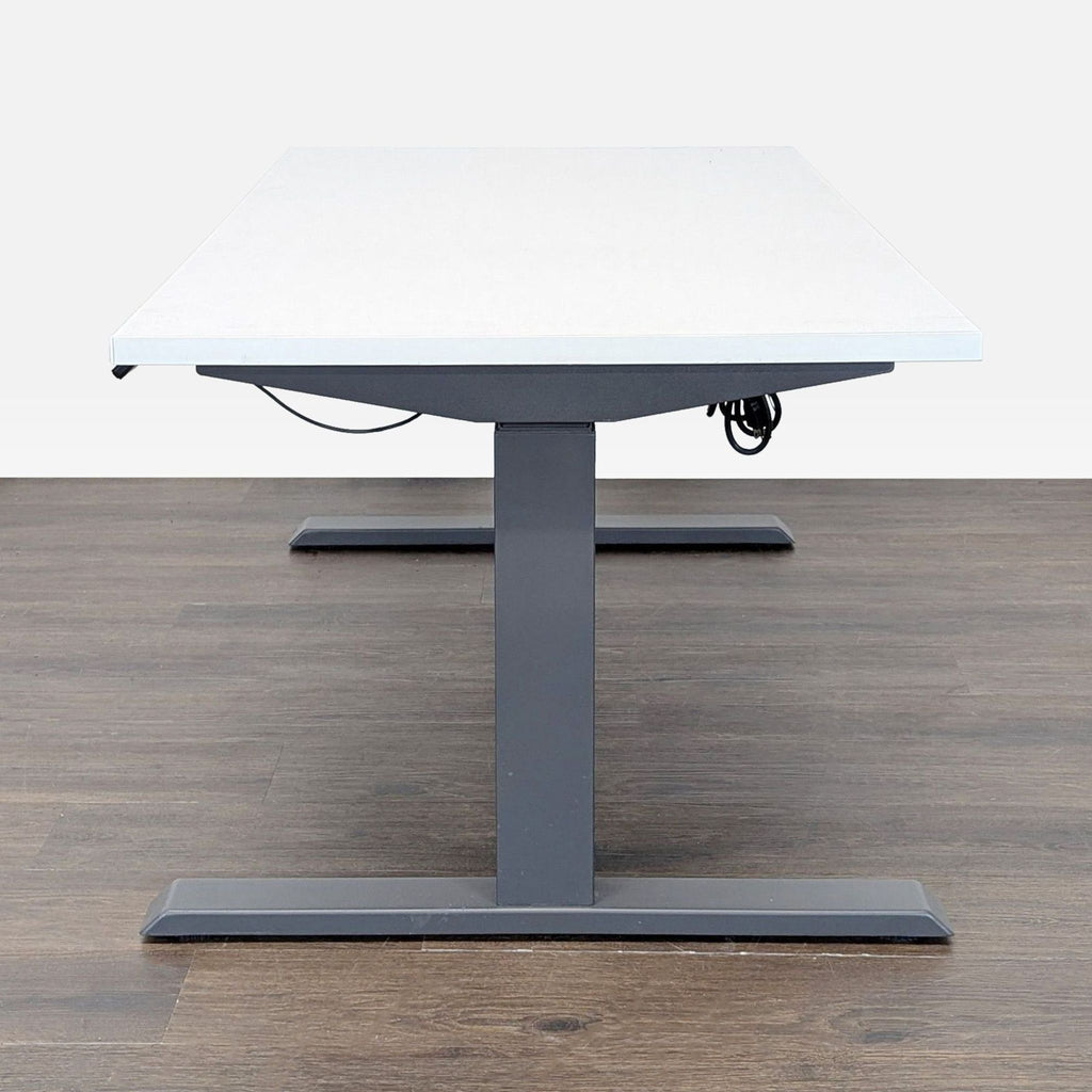 3. Side view of a Steelcase height adjustable desk, featuring a white surface and sturdy gray base.