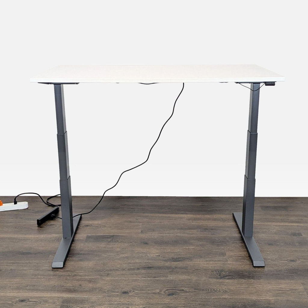 2. Steelcase white and gray electric standing desk, raised to standing height with power cord visible.  