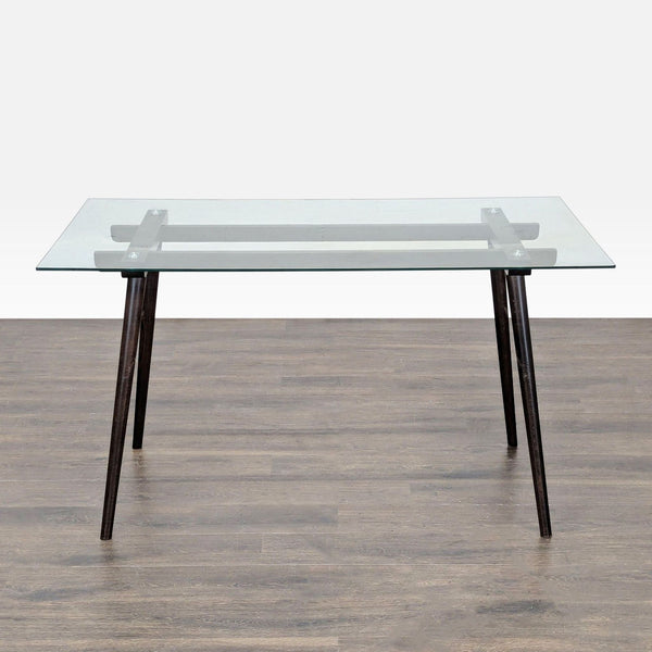 1. Rectangular dining table with a clear glass top and angled dark wooden legs, shown on a wood floor.