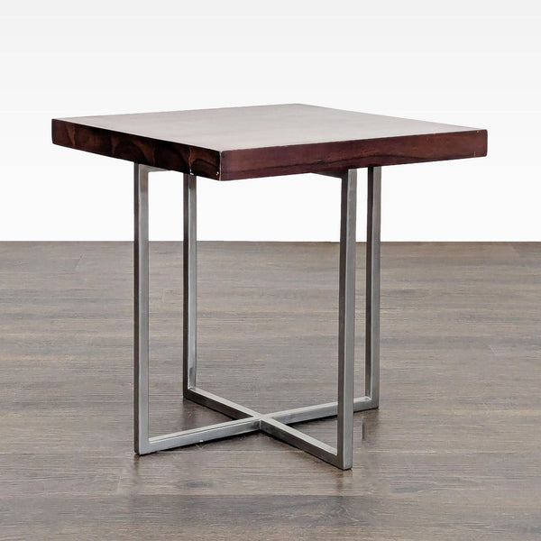 1. Modern end table with a thick square wood top and sleek metal cross legs, shown on a wood floor.  