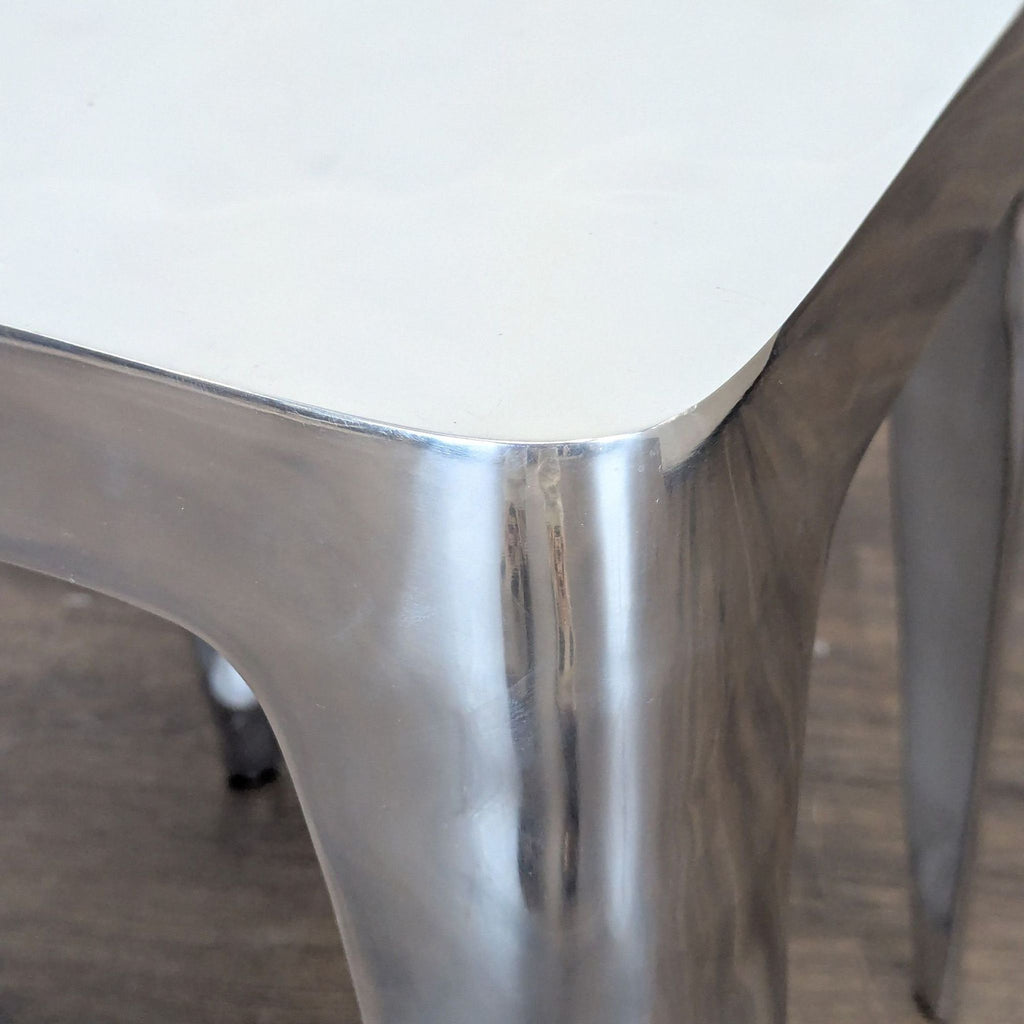 3. Close-up of a polished metal side table corner, showing smooth, reflective surfaces and rounded edges.