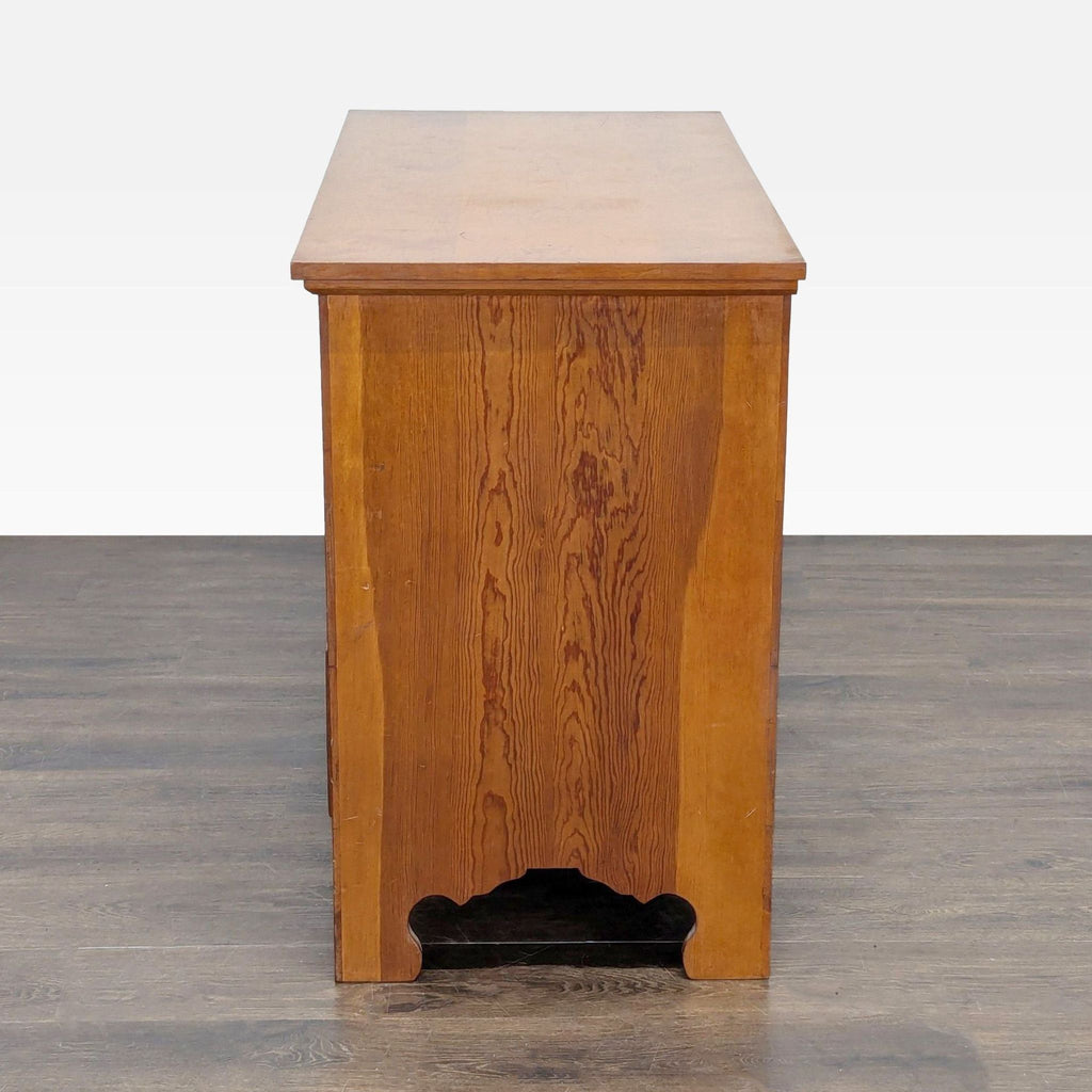 3. Side view of a wooden trunk with a simple design and carved feet, showing wood grain detail.