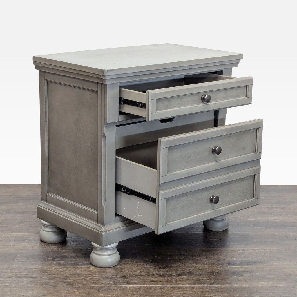 Ashley Furniture nightstand featuring burnished gray finish, silver-tone hardware, hidden tray, and roomy storage.
