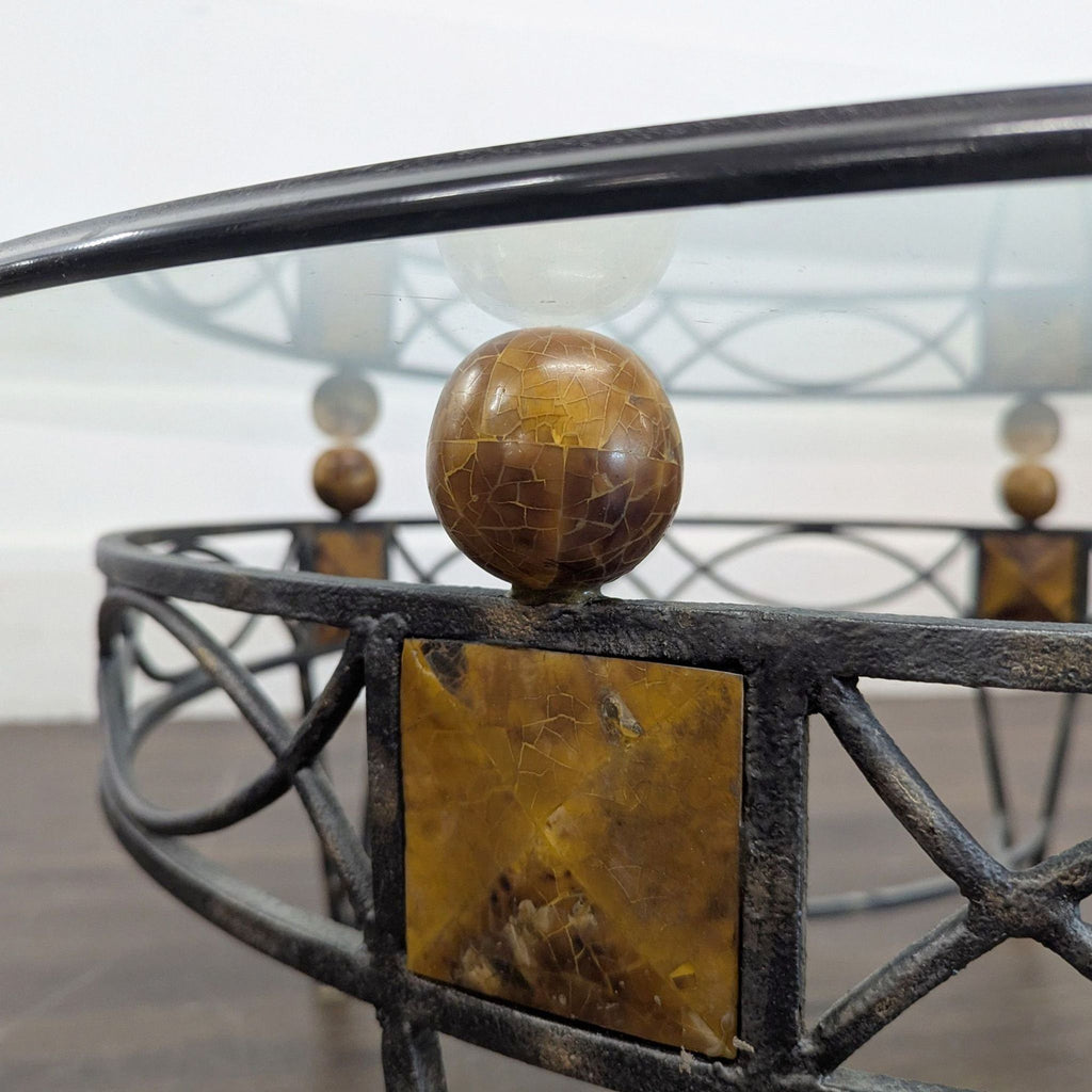 3. Detailed view of the metal coffee table’s decorative brown marble sphere and square accent beneath the glass top.