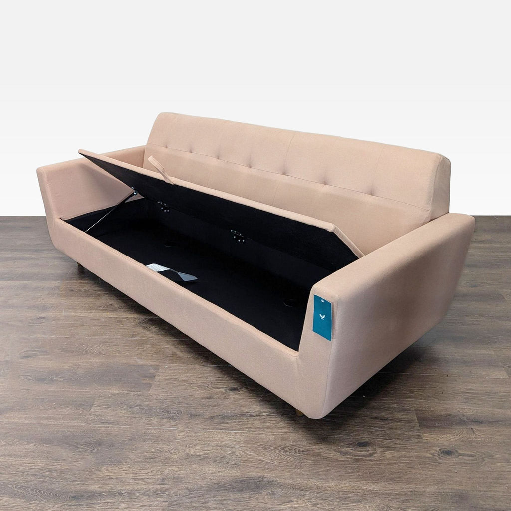 2. Beige 3-seat Joybird sofa with seat lifted showing built-in storage compartment, angled side view.