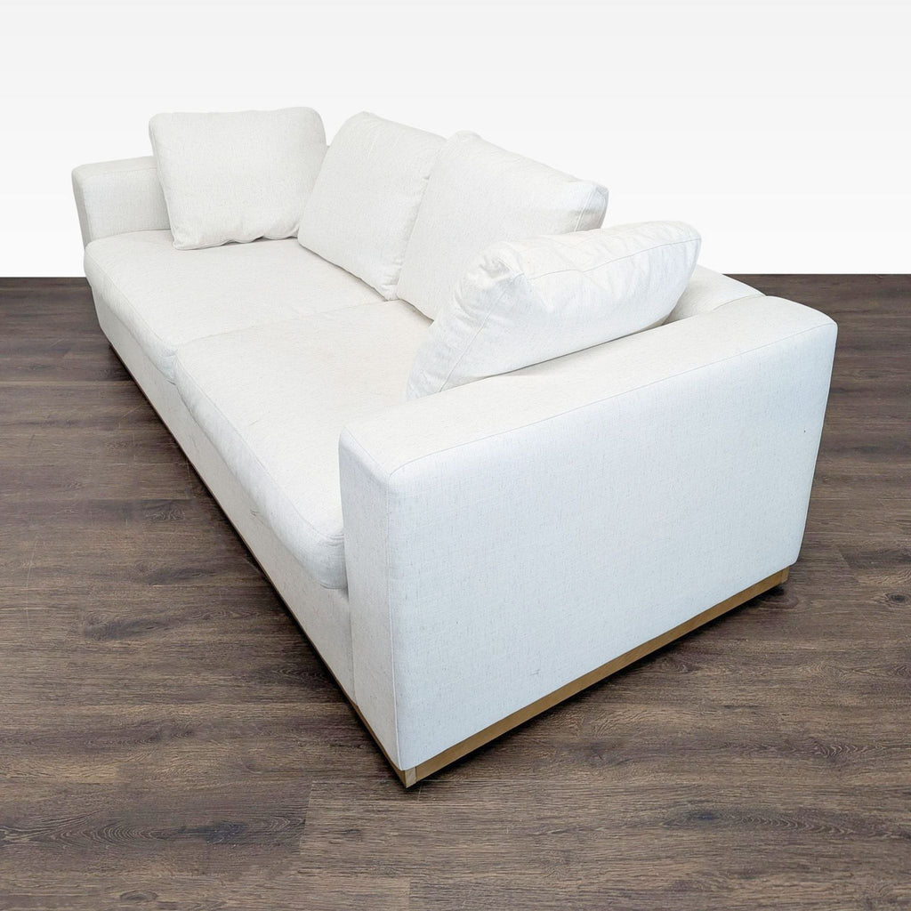 Angled side view of a neutral West Elm 3-seat couch, highlighting its plush cushions and modern design.  