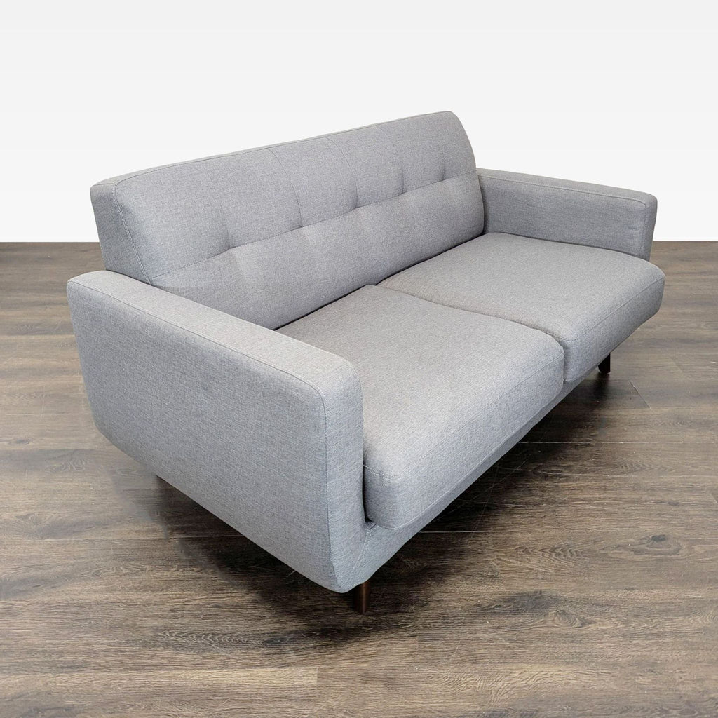 Modern Living Spaces loveseat featuring comfy cushions, mid-century wooden legs, and compact gray upholstery.