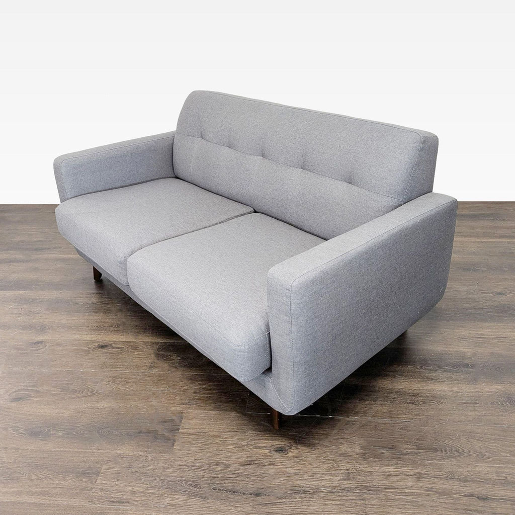 Compact gray loveseat by Living Spaces, boasting soft cushions, sleek design, and sturdy wood legs for small spaces.
