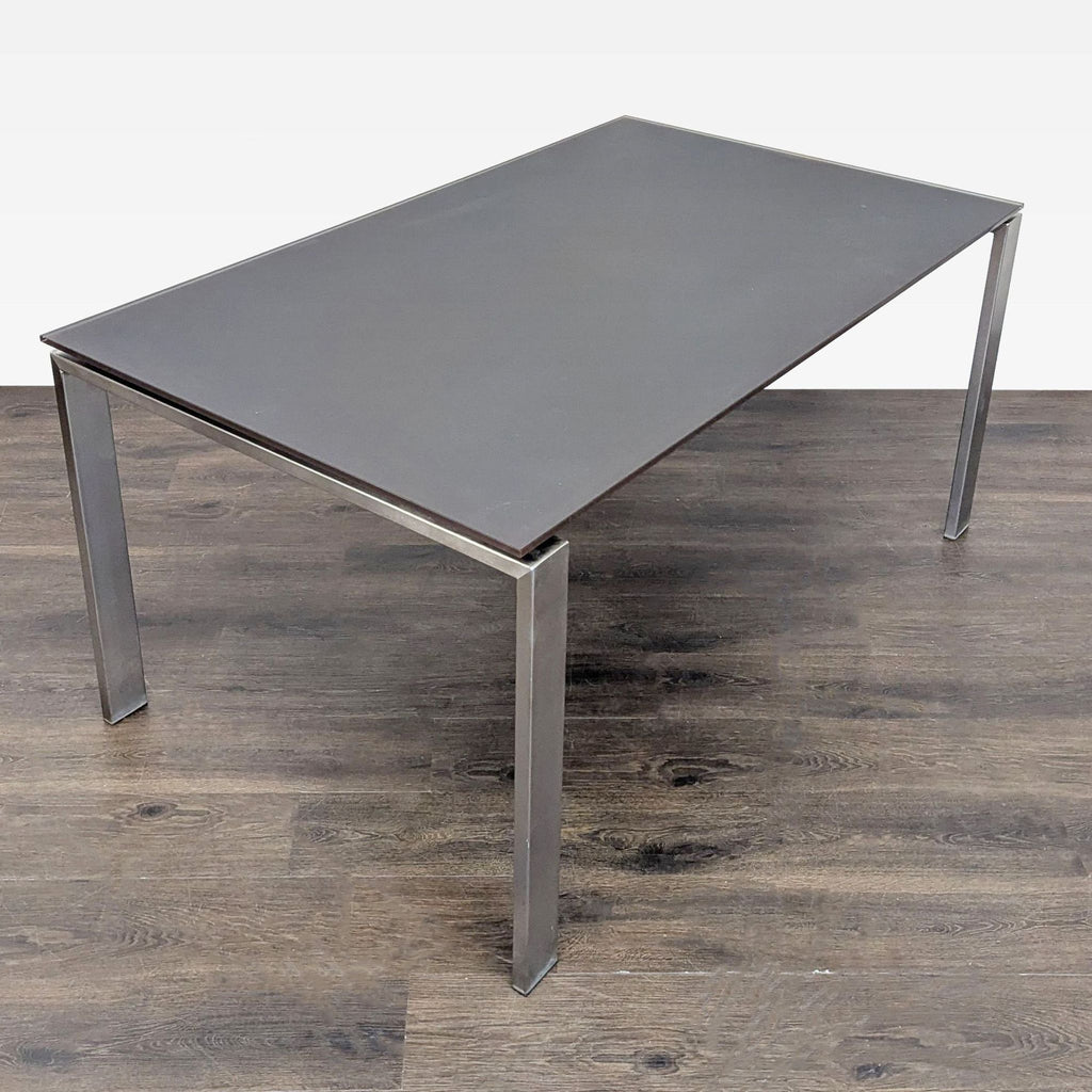 2. Modern Room & Board dining table featuring a sleek dark glass surface and sturdy metal legs.