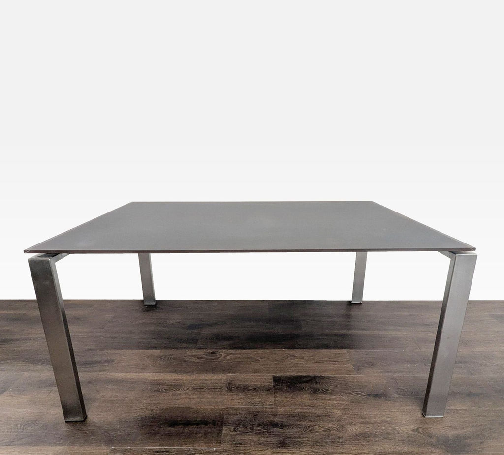 1. Rectangular Room & Board table with a dark glass top and metal frame, shown on a wooden floor.