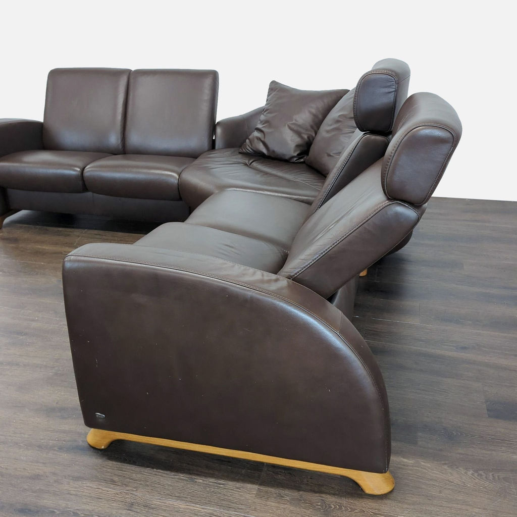 2. Close-up side view of Stressless sectional showing padded seats, armrests, and soft brown leather finish.  