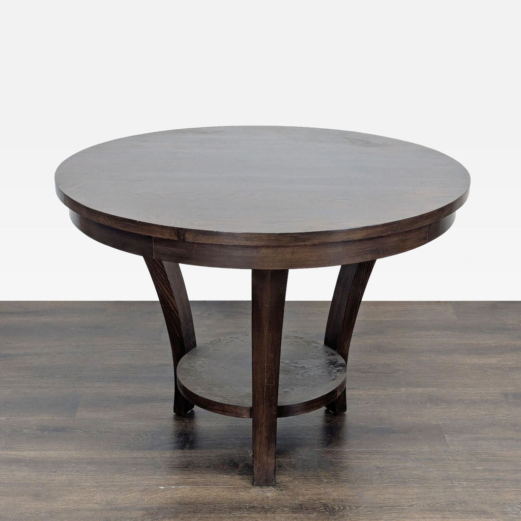2. Modern circular dining table in rich wood finish, featuring arched legs and a central support shelf.