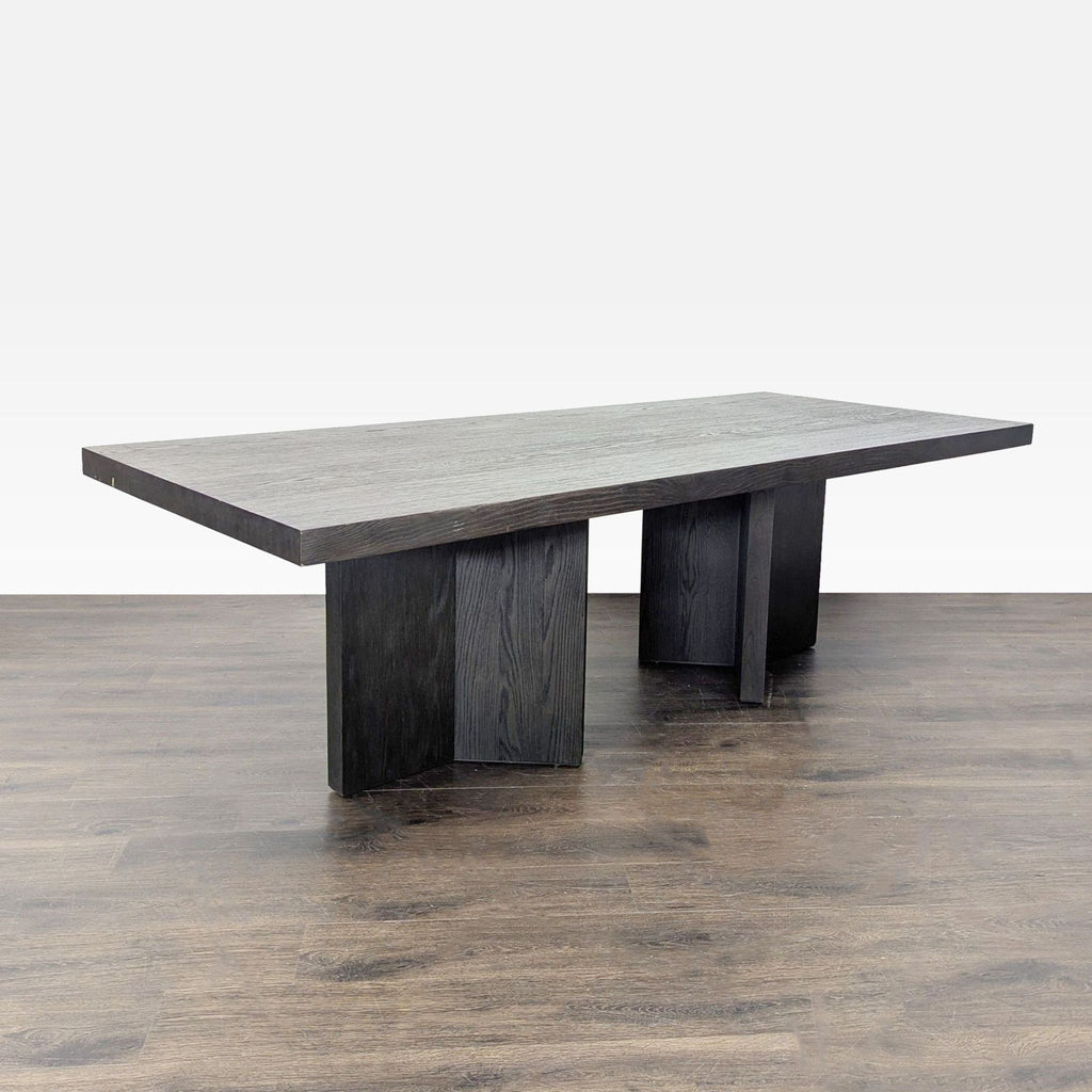 3. Angled view of Restoration Hardware dining table in dark finish, supported by two wide, block-style legs.