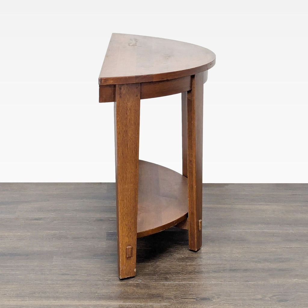 2. Side angle of a Pottery Barn half-moon side table showing two sturdy legs and curved wooden shelf.