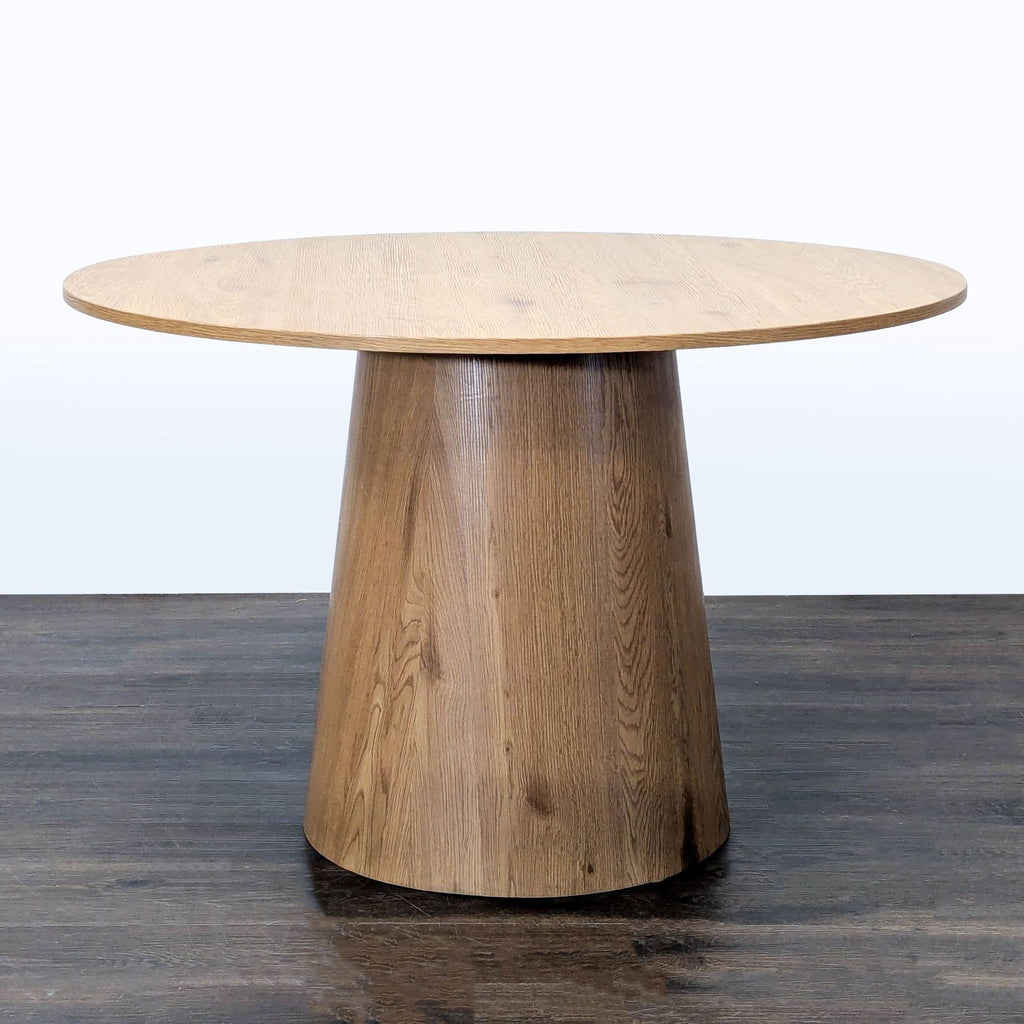 1. Round wood dining table with a cone-shaped pedestal base on a dark floor, shown from the front.