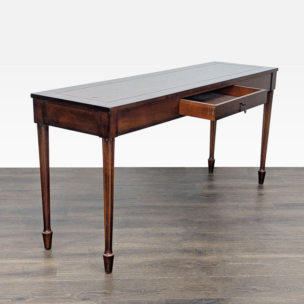 2. Side table with slim legs and an open central drawer, crafted from dark wood, on a hardwood floor.