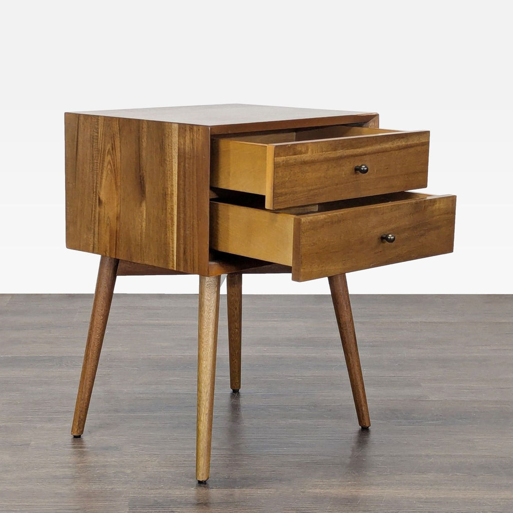 Modern end table featuring beveled front edges, angular base, and sleek tapered legs by West Elm.  