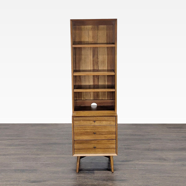 1. Front view of a tall West Elm bookshelf with three shelves and three drawers on mid-century legs.  