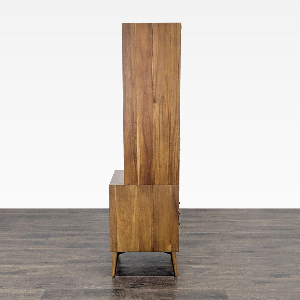 3. Side profile of a tall West Elm bookshelf with a wood finish and tapered legs.