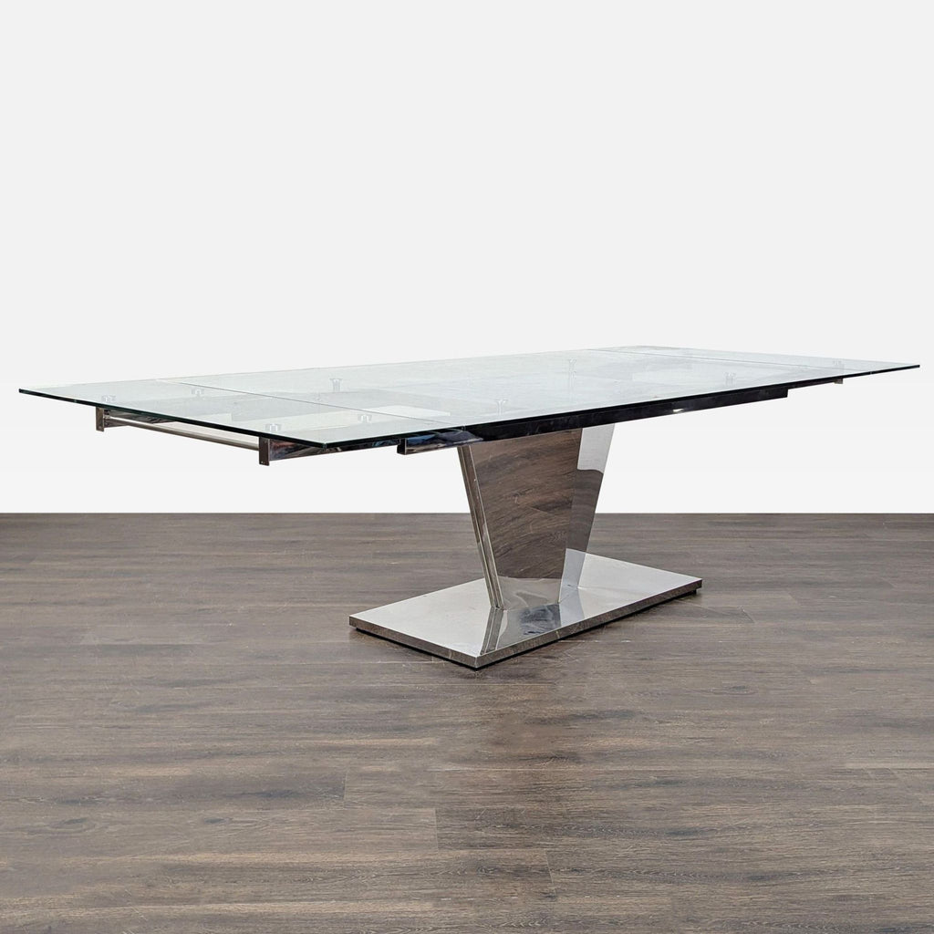 3. Sleek dining table with a transparent glass surface and angular metal pedestal, expands up to 110.75 inches.
