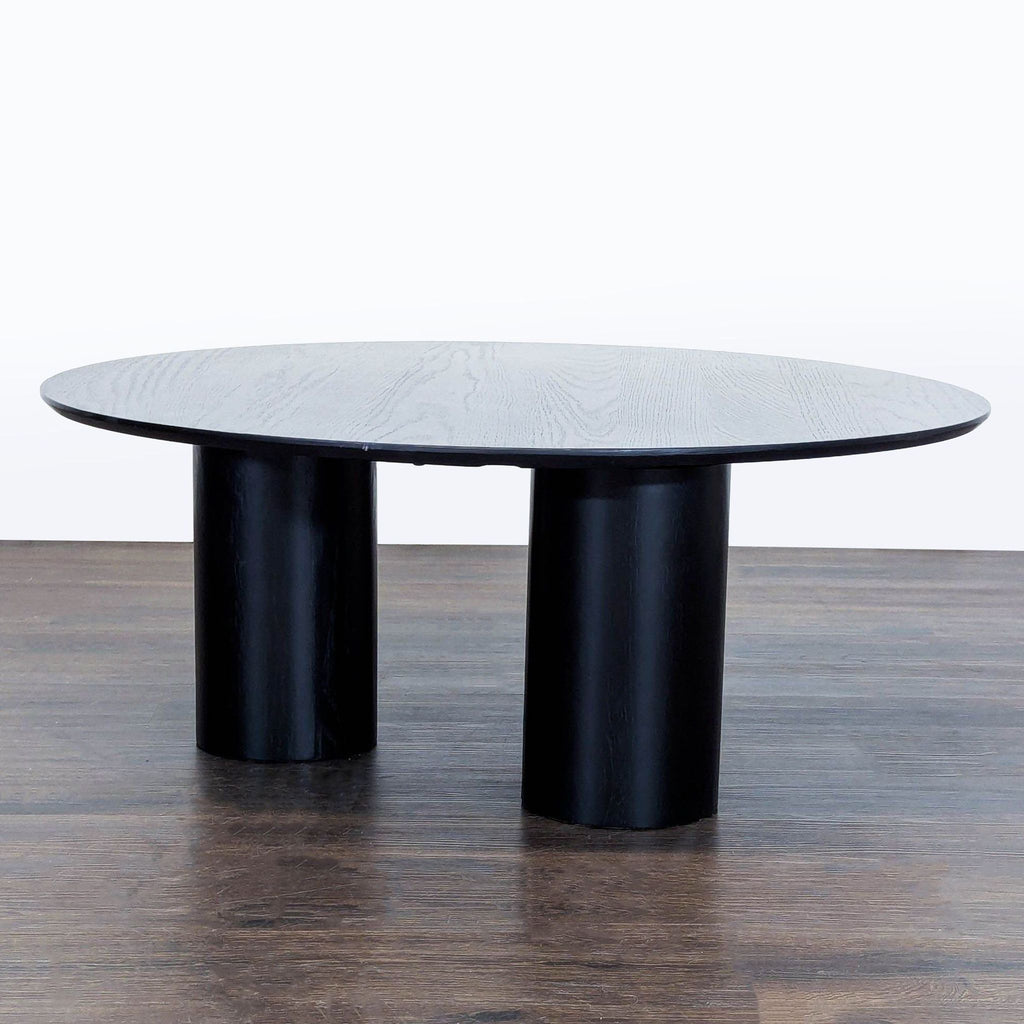 Bold, contemporary coffee table with a round silhouette and three thick legs by Ivy Bronx.